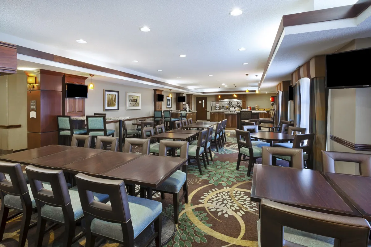 This space is arranged with tables set for dining or meetings, featuring a decorative carpet and soft lighting. The atmosphere is welcoming and communal, encouraging guests to gather for meals, snacks, or group activities in a comfortable setting.