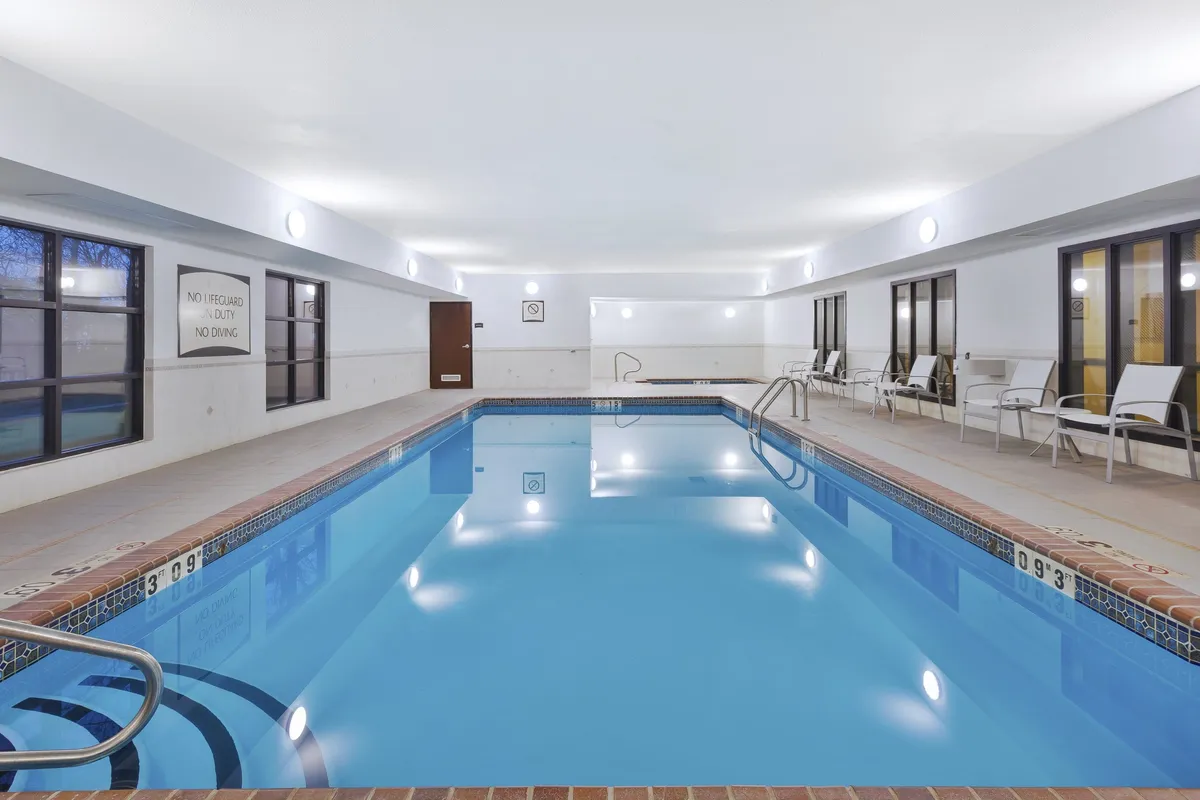 A tranquil indoor swimming pool space with lounge chairs and large windows allowing plenty of natural light. The setting is calm, offering opportunities for relaxation or socializing after a productive workday.