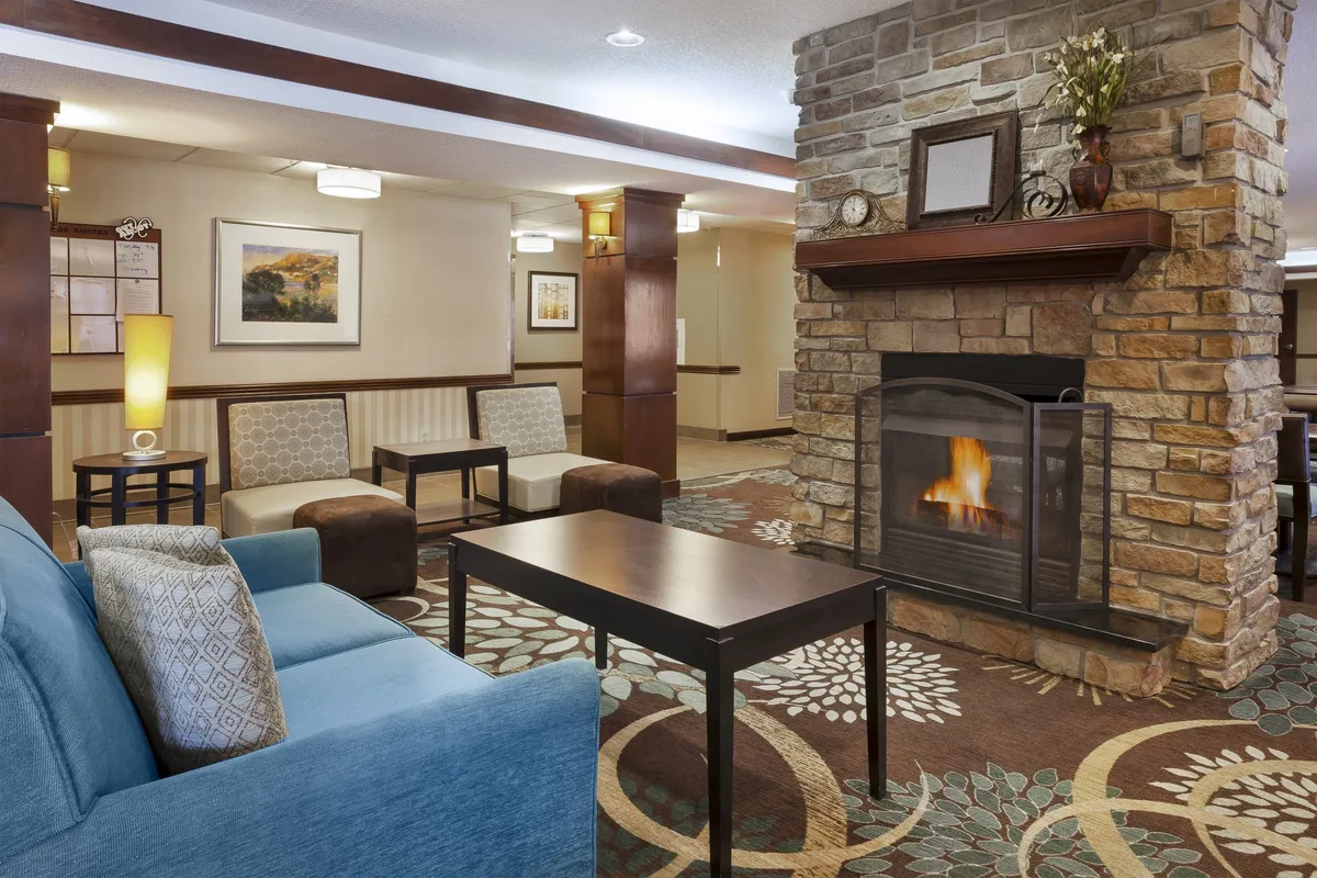 A cozy lounge area with a fireplace, plush sofa, coffee table, and tasteful artwork on the walls. The scene evokes relaxation, social connection, and quiet moments of reflection by the fire.