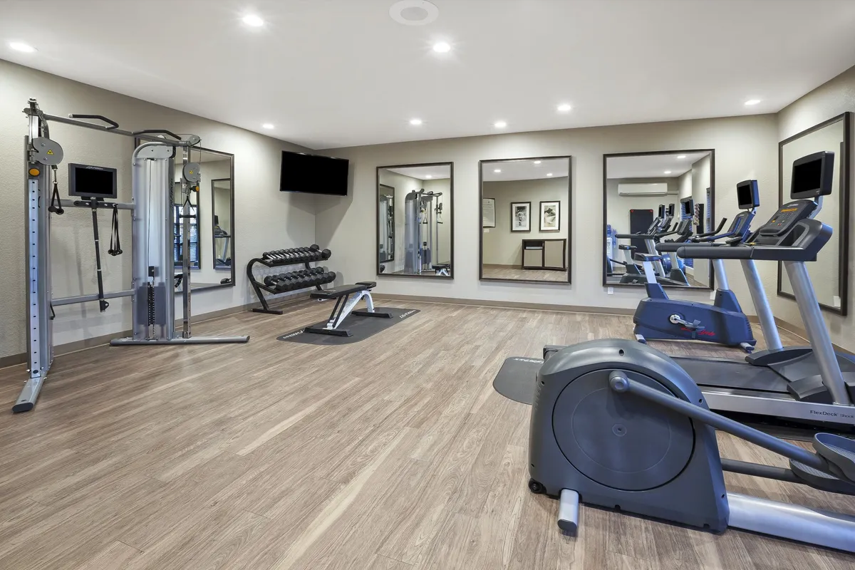 A spacious, well-equipped fitness center with a variety of gym machines, free weights, and mirrors. The environment appears motivational and inviting for guests looking to stay active during their stay.